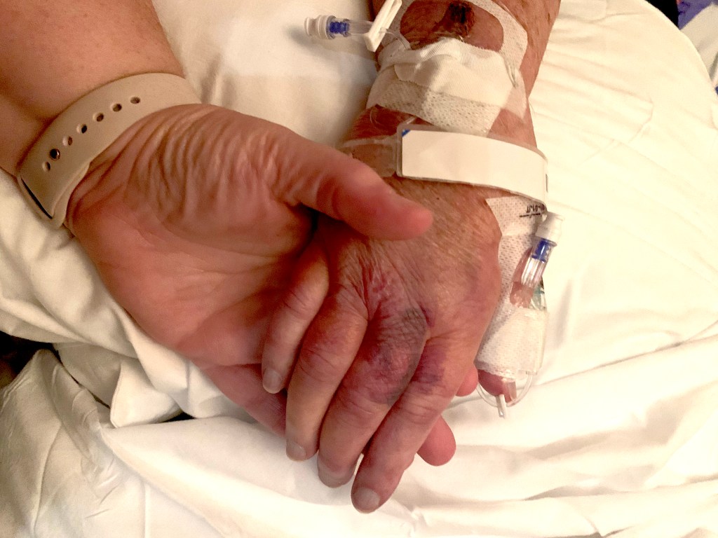 A photo of my holding my momma's hand for the final time. 